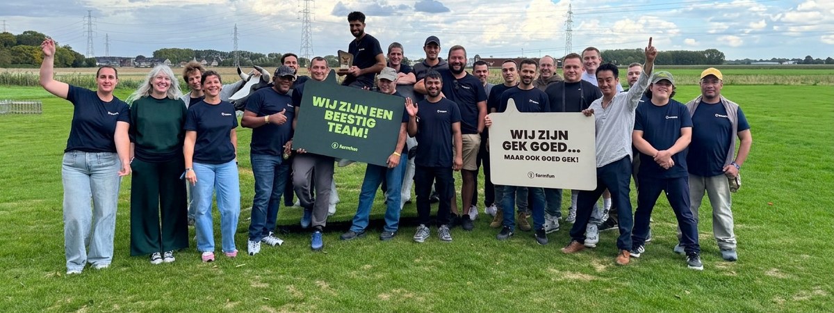 Groepsfoto van het team van Empro buiten op het gras met twee sfeerpanelen