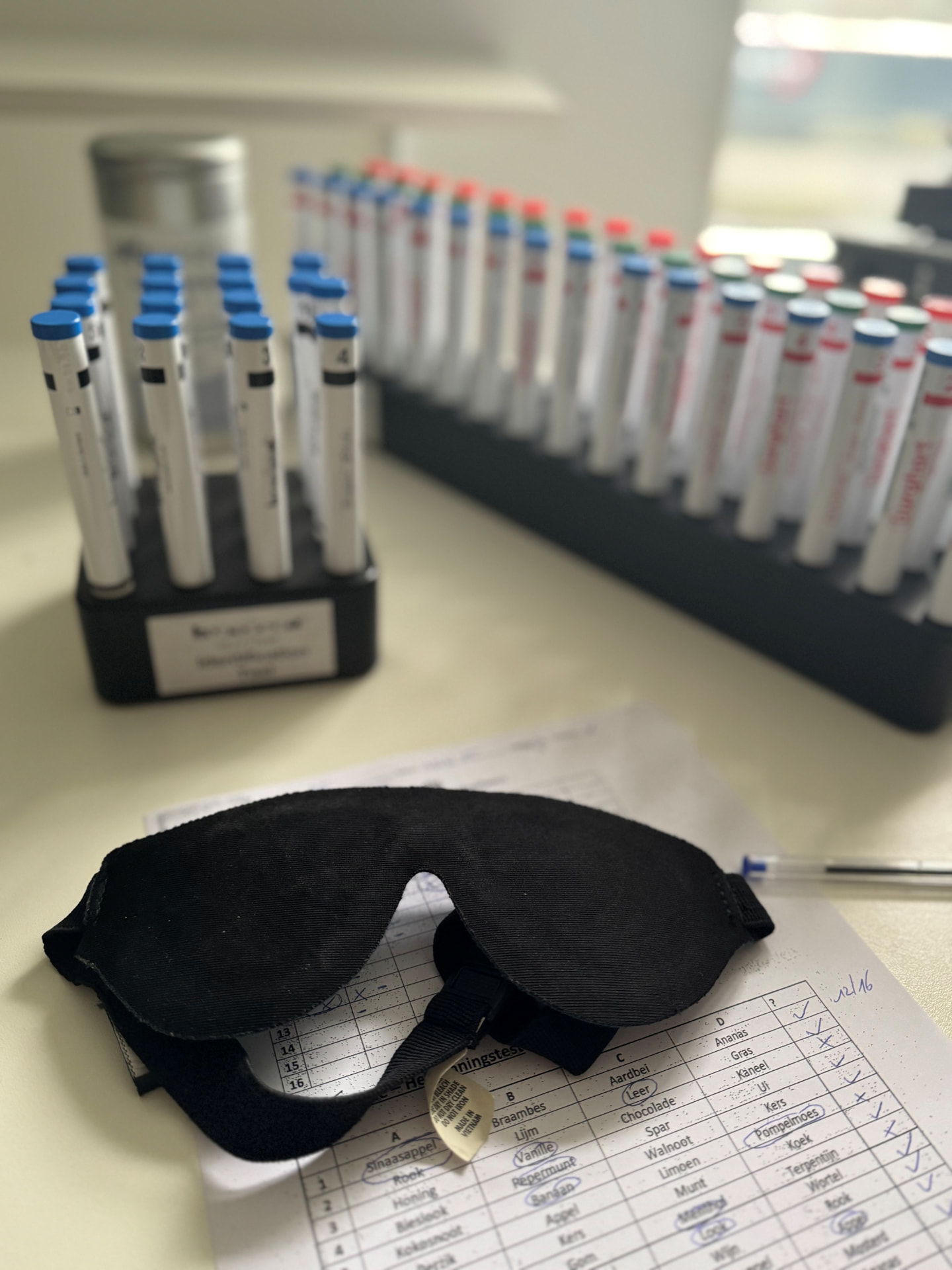 Slaapmasker op een scoreformulier voor een geurtest met genormeerde geurstiften in zwarte houders