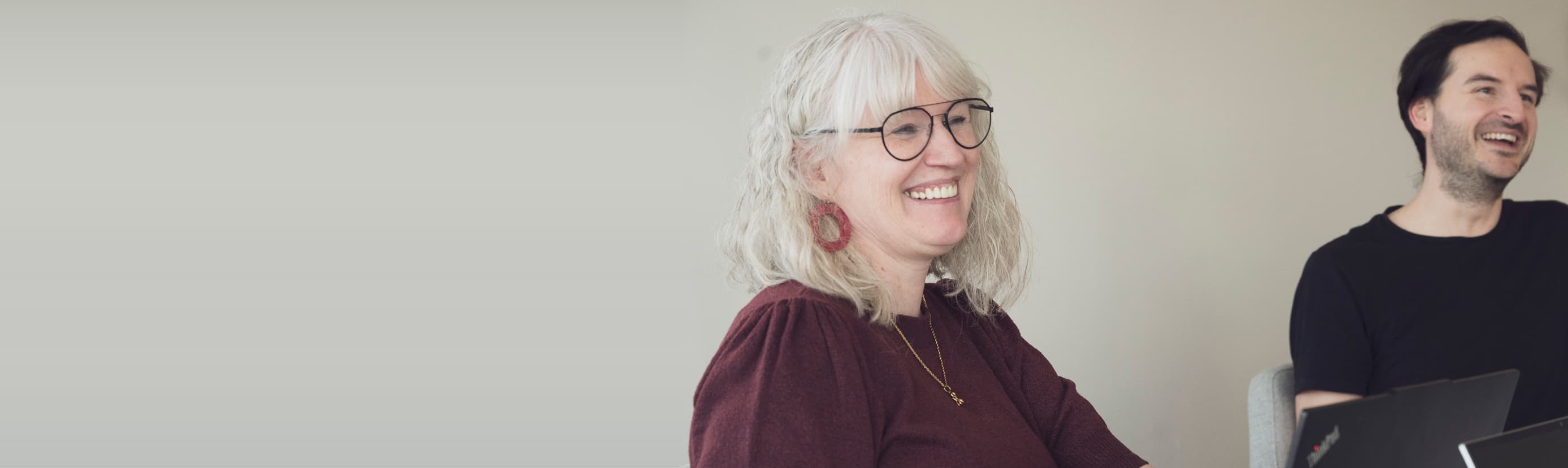 Collega's van Empro lachen tijdens een overleg aan tafel met laptops