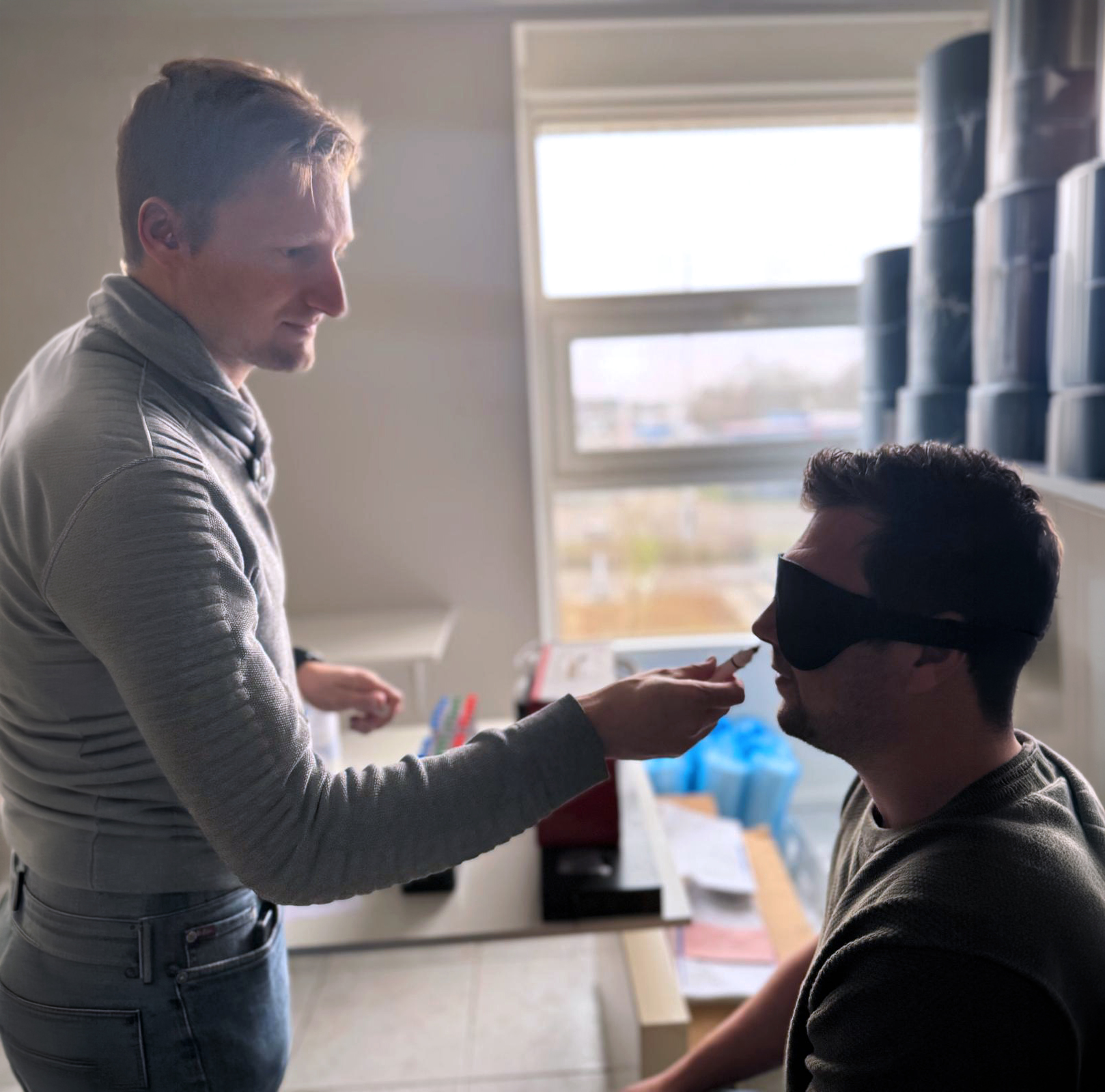 Medewerker houdt een geurpen onder de neus van een collega met een oogmasker